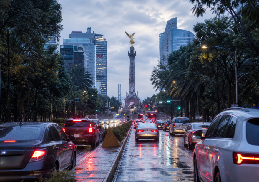 Avenida de la Ciudad de México con tráfico matutino, pavimento mojado y cielo nublado tras la lluvia.