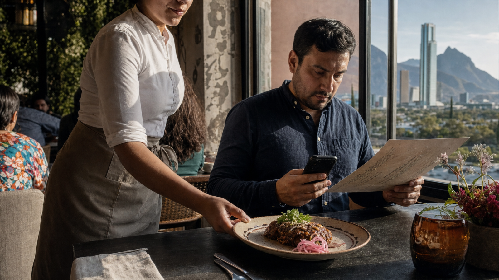 Mesero acerca un plato a una mesa mientras una persona revisa el menú y calcula el gasto en su teléfono, en un restaurante urbano de San Pedro Garza García.