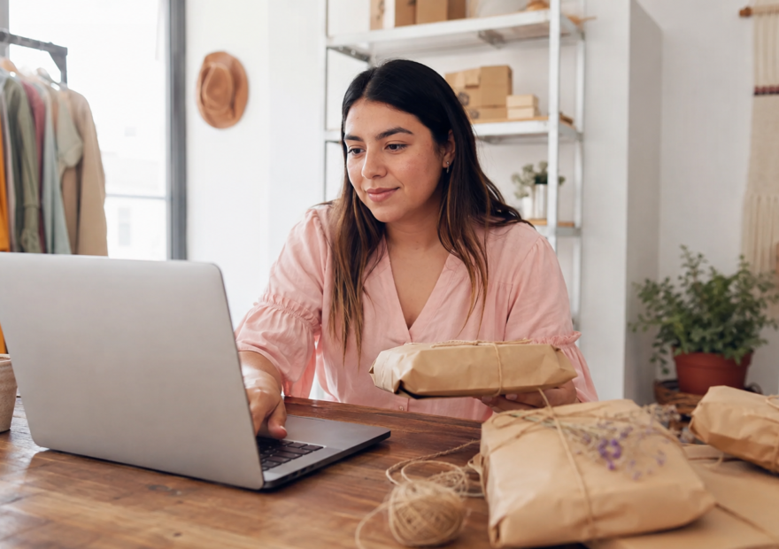 Emprendedora mexicana organizando pedidos digitales y empaques artesanales en un pequeño negocio.