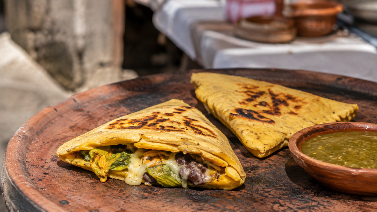 Itacates tradicionales recién cocidos sobre un comal de barro, acompañados de salsa verde