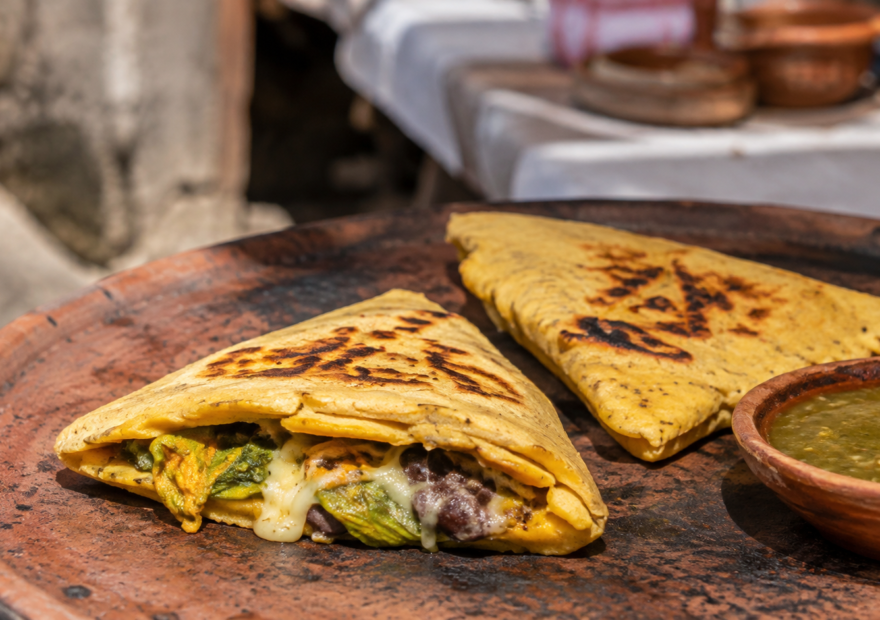 Itacates tradicionales recién cocidos sobre un comal de barro, acompañados de salsa verde